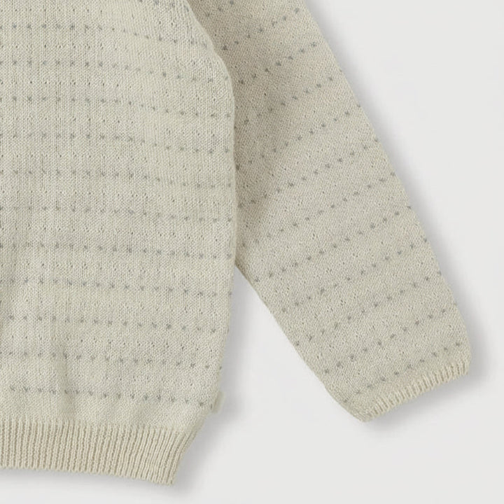 Cream cardigan sleeve and hem detail showing pointelle knitting and ribbed trim