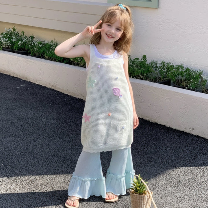 Front view of a girl wearing the long cream knit top with pale green wide-leg pants