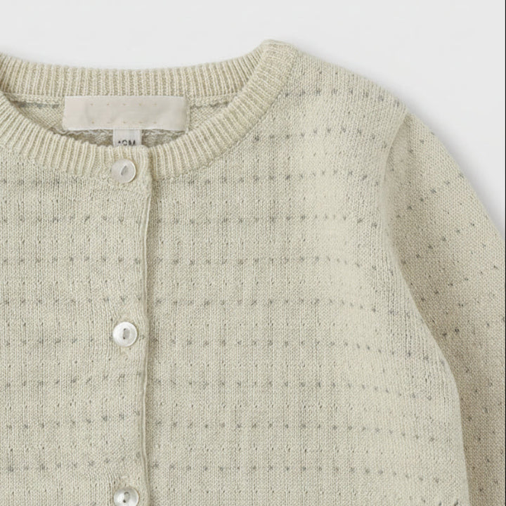 Close-up of a Cream pointelle cardigan showing the round ribbed neckline and front buttons