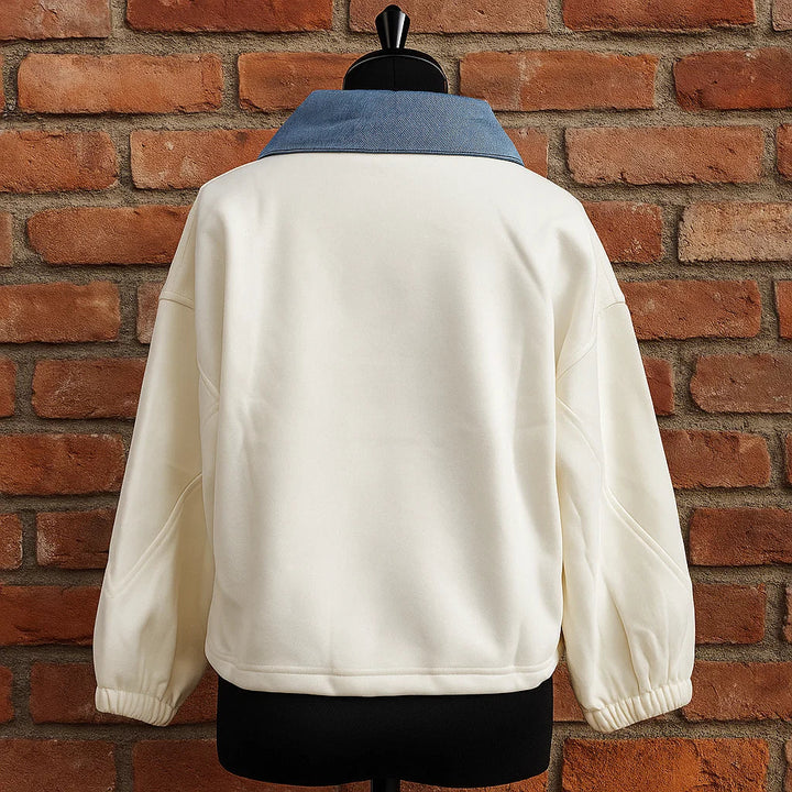 Back of the cream polo on a dress form, with a blue denim collar and gathered sleeve cuffs