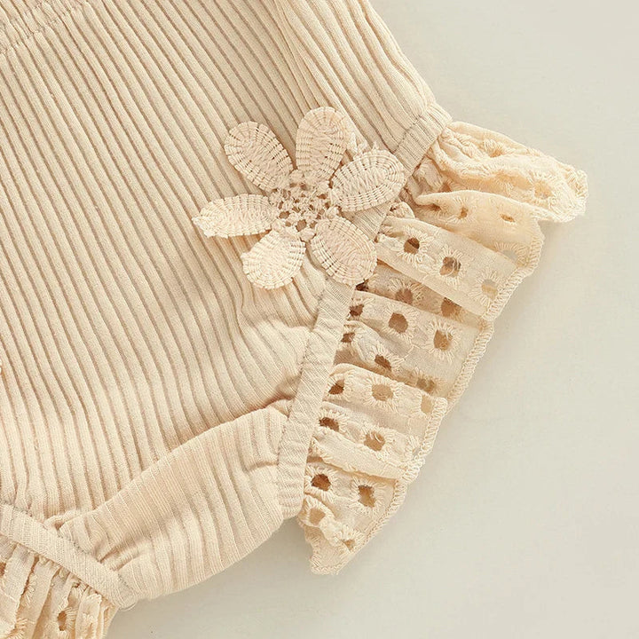 Cream ribbed shorts with a flower applique beside the ruffled leg opening