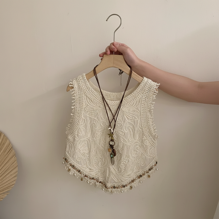 Cream sleeveless crochet top showing its textured pattern and pointed, fringed hem