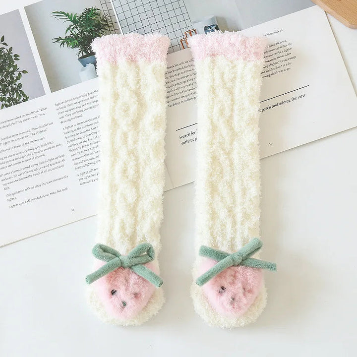 Pair of cream-colored strawberry socks with pink cuffs and green bows