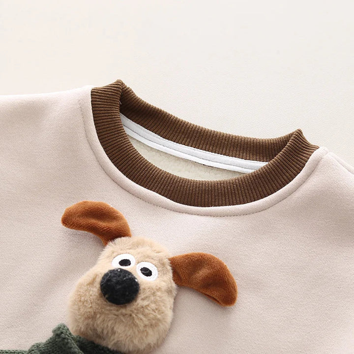 Close-up of the ribbed brown neckline and raised puppy detail on the cream sweater front