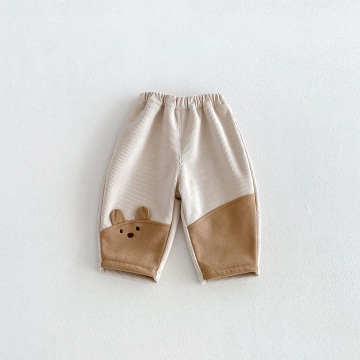 Cream and tan pants with an elastic waistband and animal-face detail near the hem
