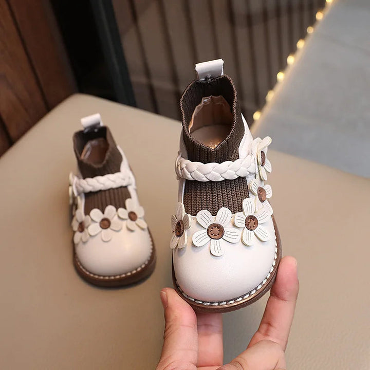 Cream White floral ankle boot with a dark ribbed cuff, light braided trim, and brown sole.