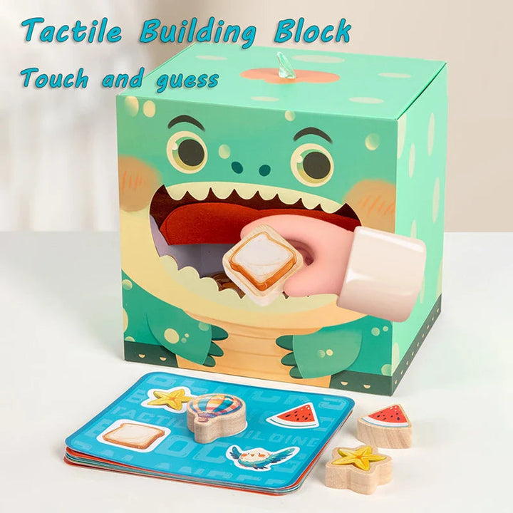 Hand holding a bread-shaped wooden block at the mouth opening of a crocodile play box