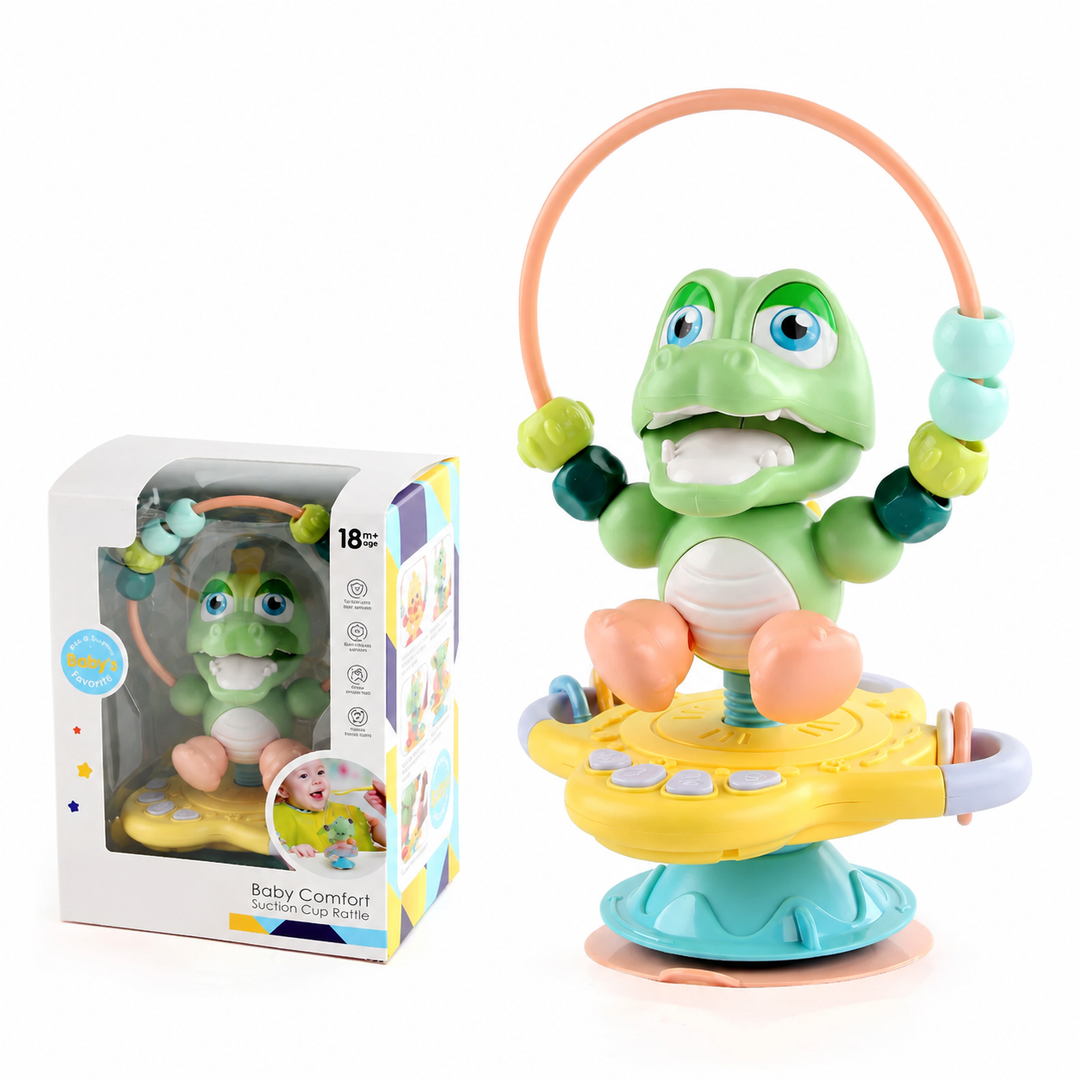 Green crocodile rattle with a bead loop and ring attachments, shown with its box