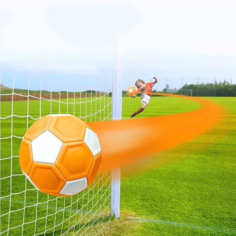 Orange-and-white soccer ball beside a goal net with an orange flight trail.