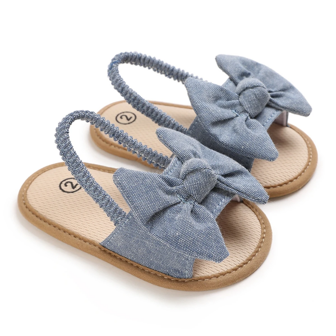 Dark blue bow baby sandals with tan footbeds shown as a pair