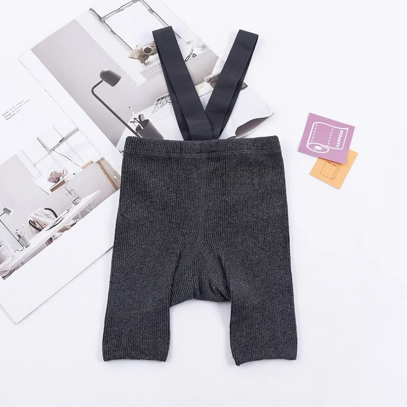 Dark gray ribbed suspender shorts laid flat with matching shoulder straps.