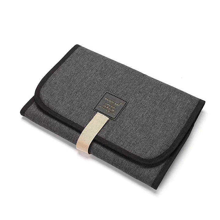 Dark gray portable changing mat with black trim and a beige front strap
