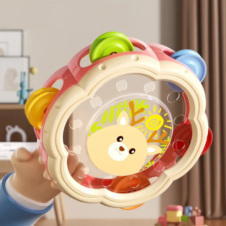 Hand holding a pink deer tambourine with an animal face and colorful jingles
