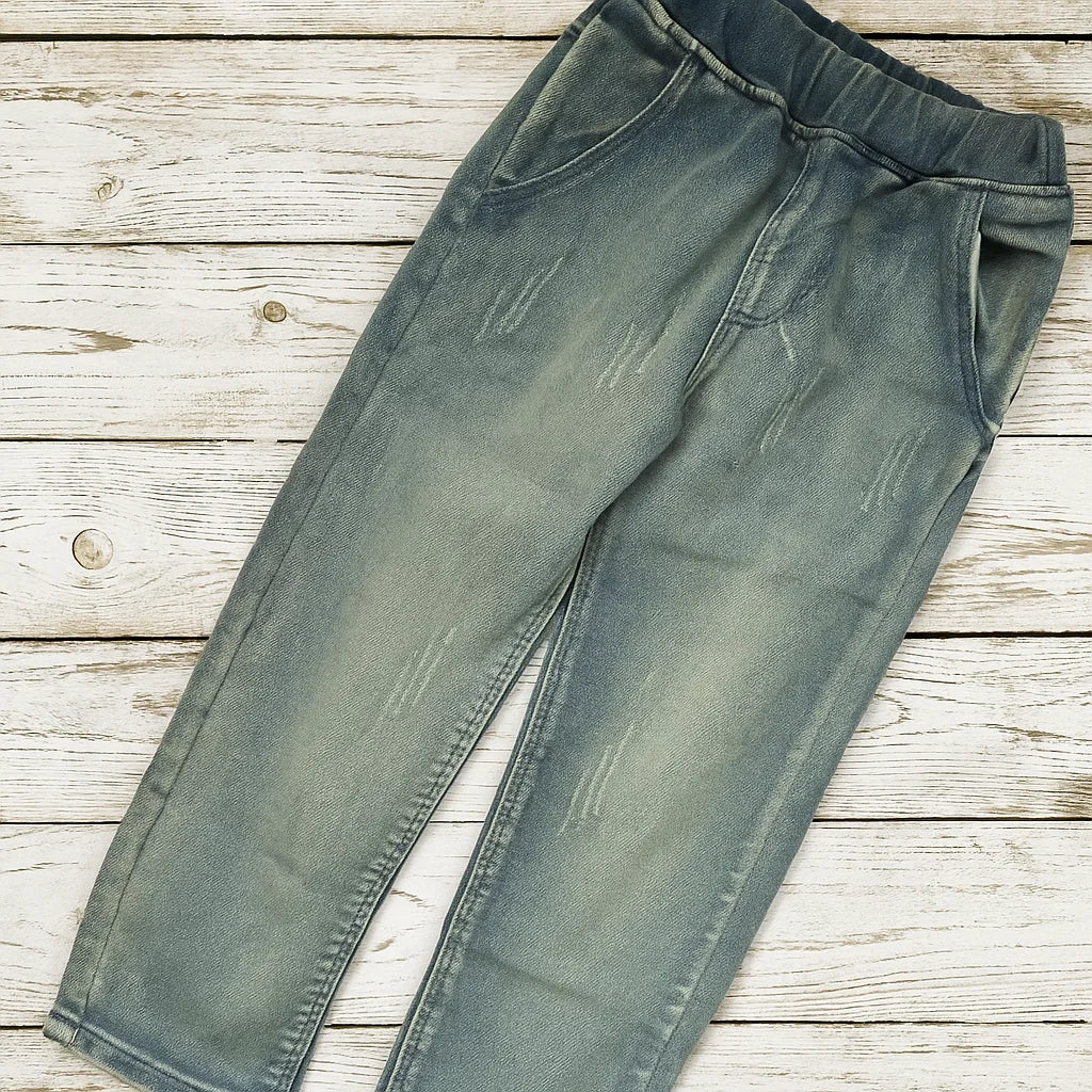 Denim pants laid flat, showing the elastic waistband, front pockets, and washed finish.