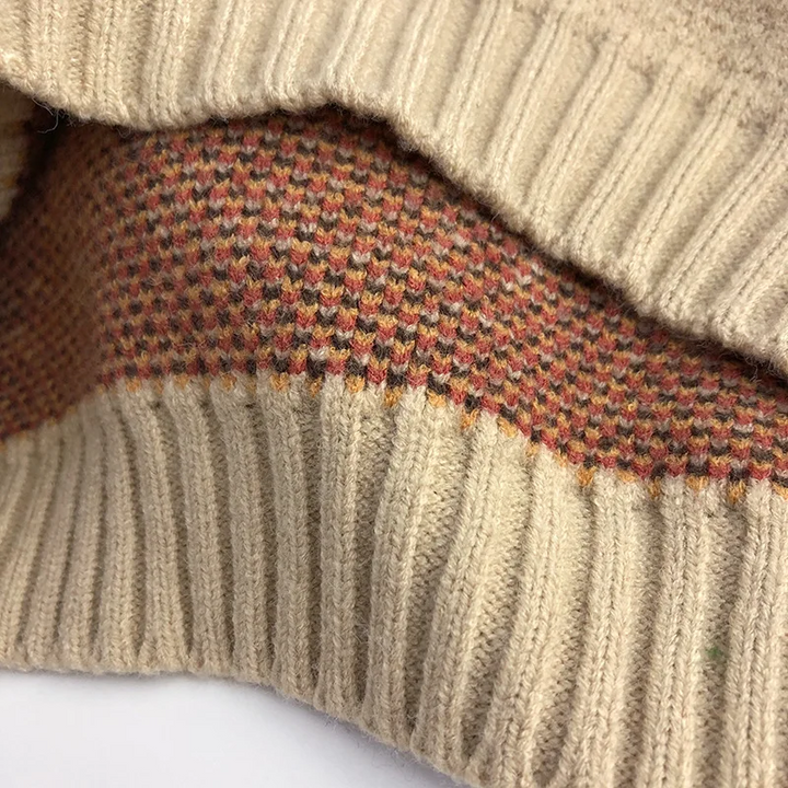 Inside of the diamond-knit sweater showing multicolored yarns and a ribbed edge