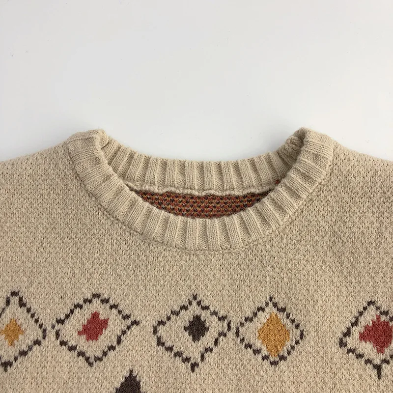 Close-up of the ribbed round neckline and small diamonds on the beige sweater