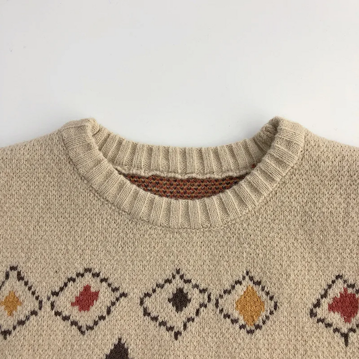 Close-up of the ribbed round neckline and small diamonds on the beige sweater