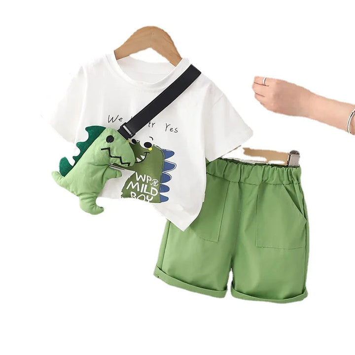 White dinosaur-print T-shirt, green shorts and matching dinosaur toy displayed on a white background