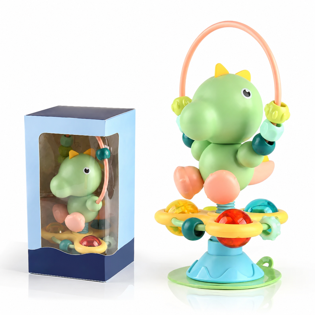 Green dinosaur rattle with a beaded loop and ball play pieces, shown beside its box