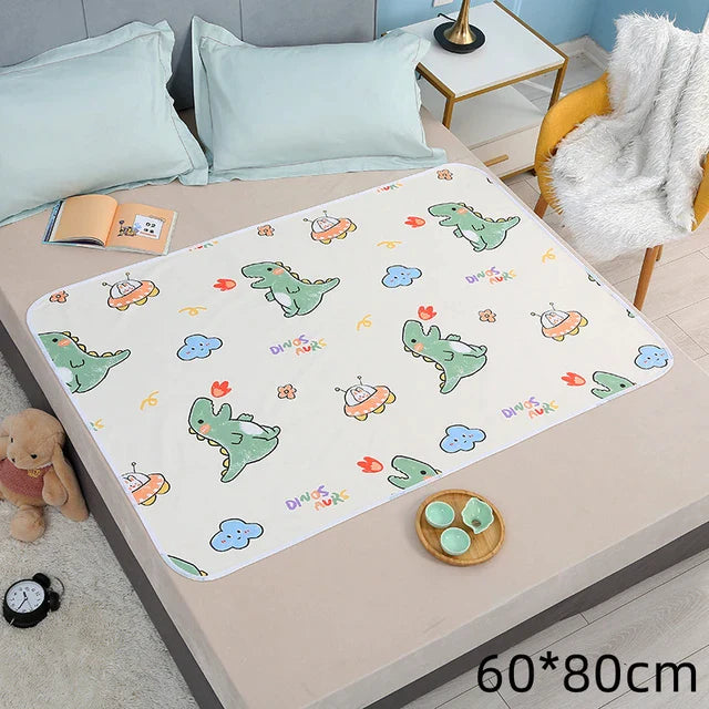 Dinosaur-print changing mat with white edging on a bed, labeled 60 x 80 cm.