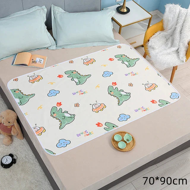 White dinosaur-print changing mat spread across a bed, labeled 70 x 90 cm.