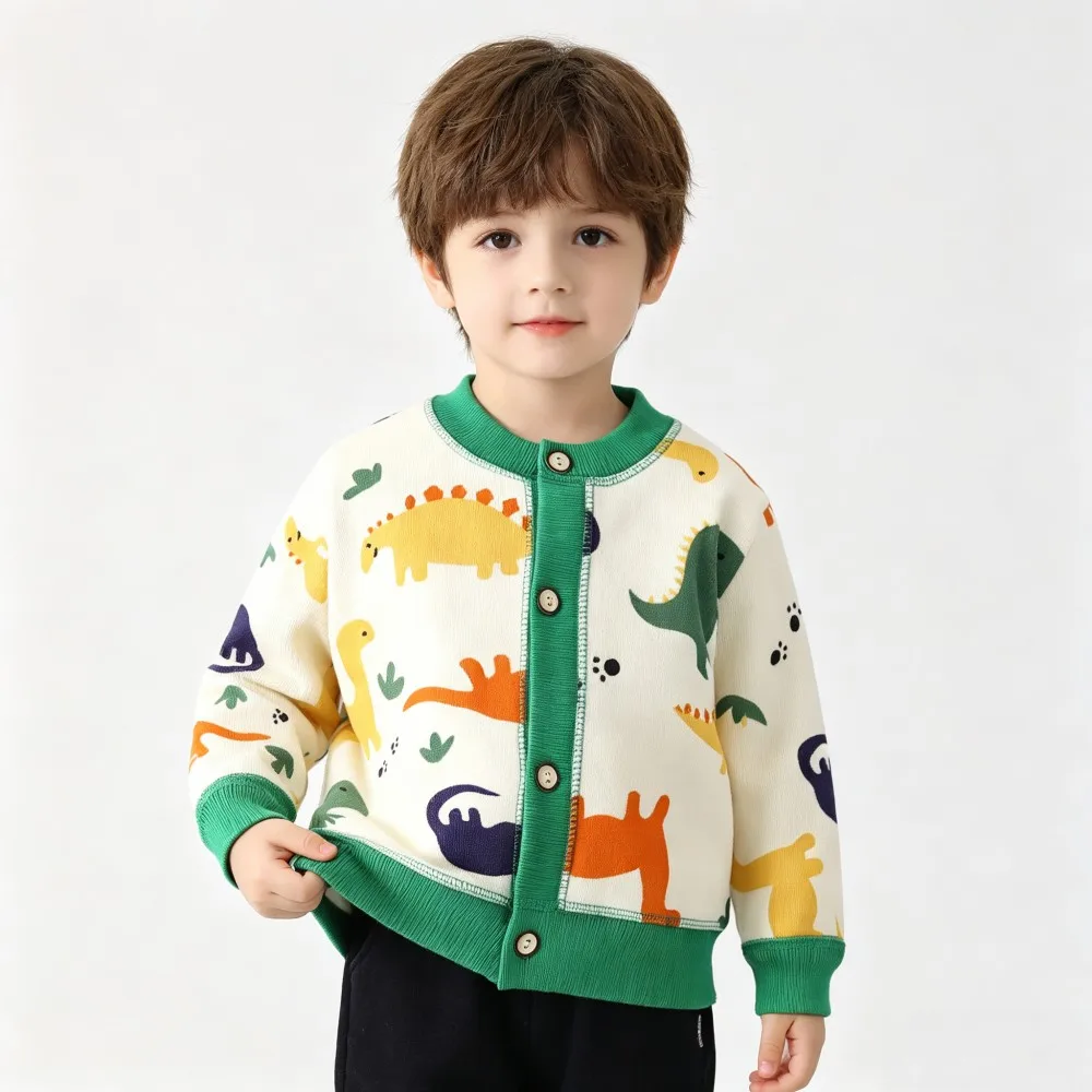 Child wearing a cream dinosaur cardigan with green trim and colorful dinosaur motifs