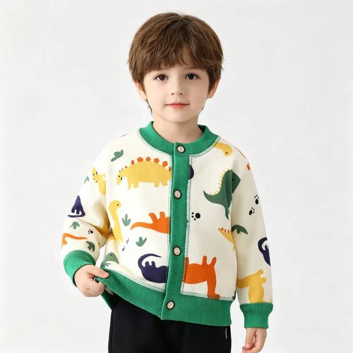 Child wearing a cream dinosaur cardigan with green trim and colorful dinosaur motifs