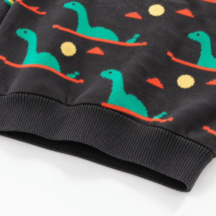 Ribbed hem on a dark knit sweater with green dinosaurs and yellow circles