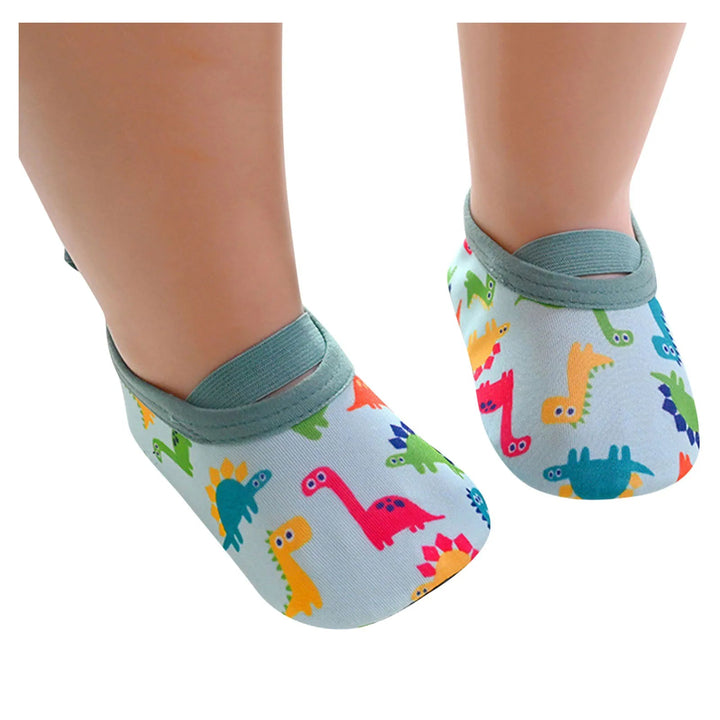 Child wearing light blue dinosaur-print water shoes with green instep straps