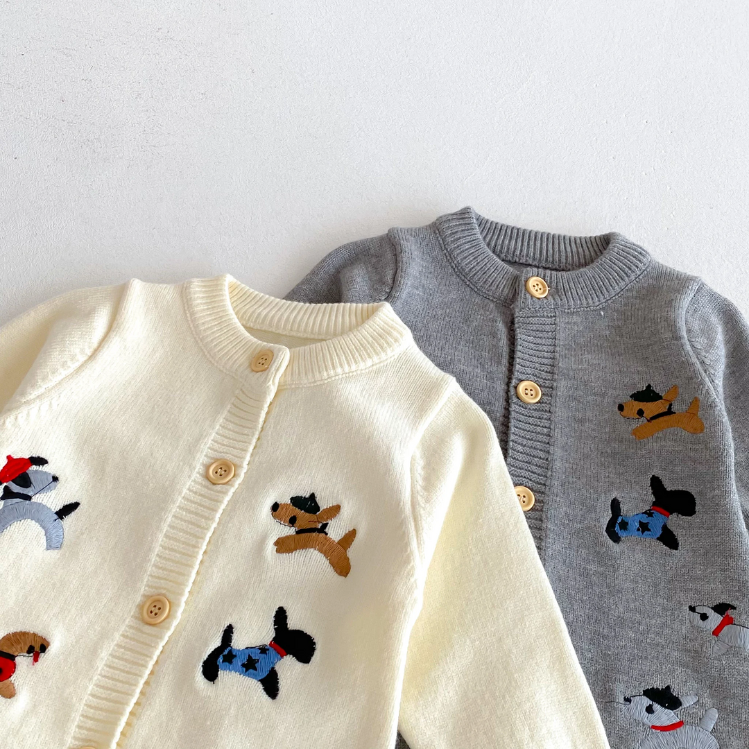 Close-up of beige and gray baby jumpsuits showing round necklines, buttons, and dog motifs