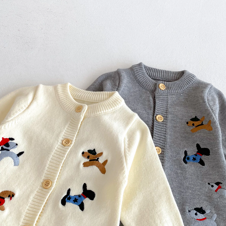 Close-up of beige and gray baby jumpsuits showing round necklines, buttons, and dog motifs