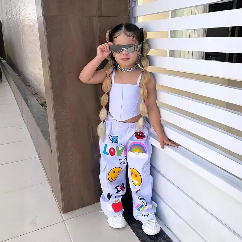 Child wearing a white cropped tank top and loose pants with colorful rainbow and smiley-face graphics