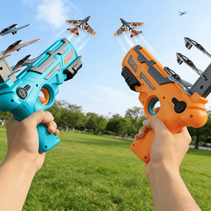Blue and orange foam airplane launchers held outdoors with planes overhead