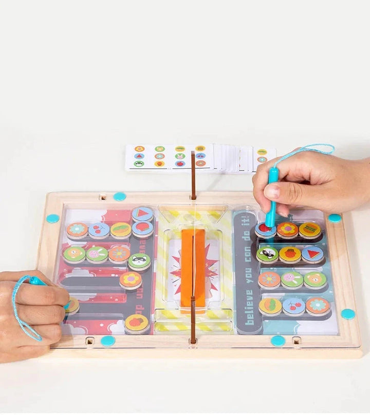 Hands use turquoise magnetic wands on opposite sides of a wooden color-matching board.