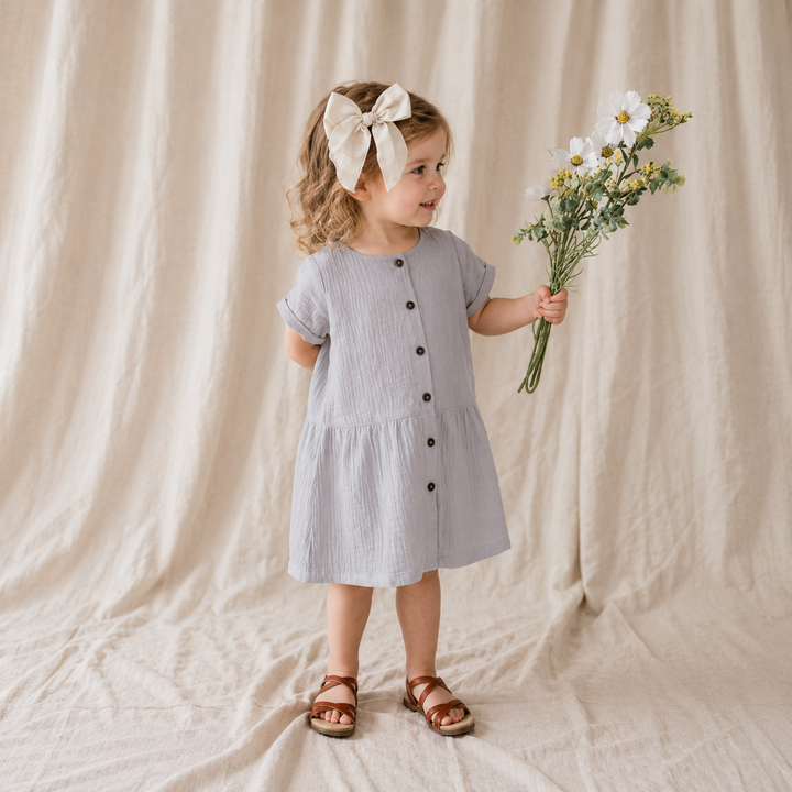 Girl wearing the Dusty Purple A-line dress with sandals and holding flowers.