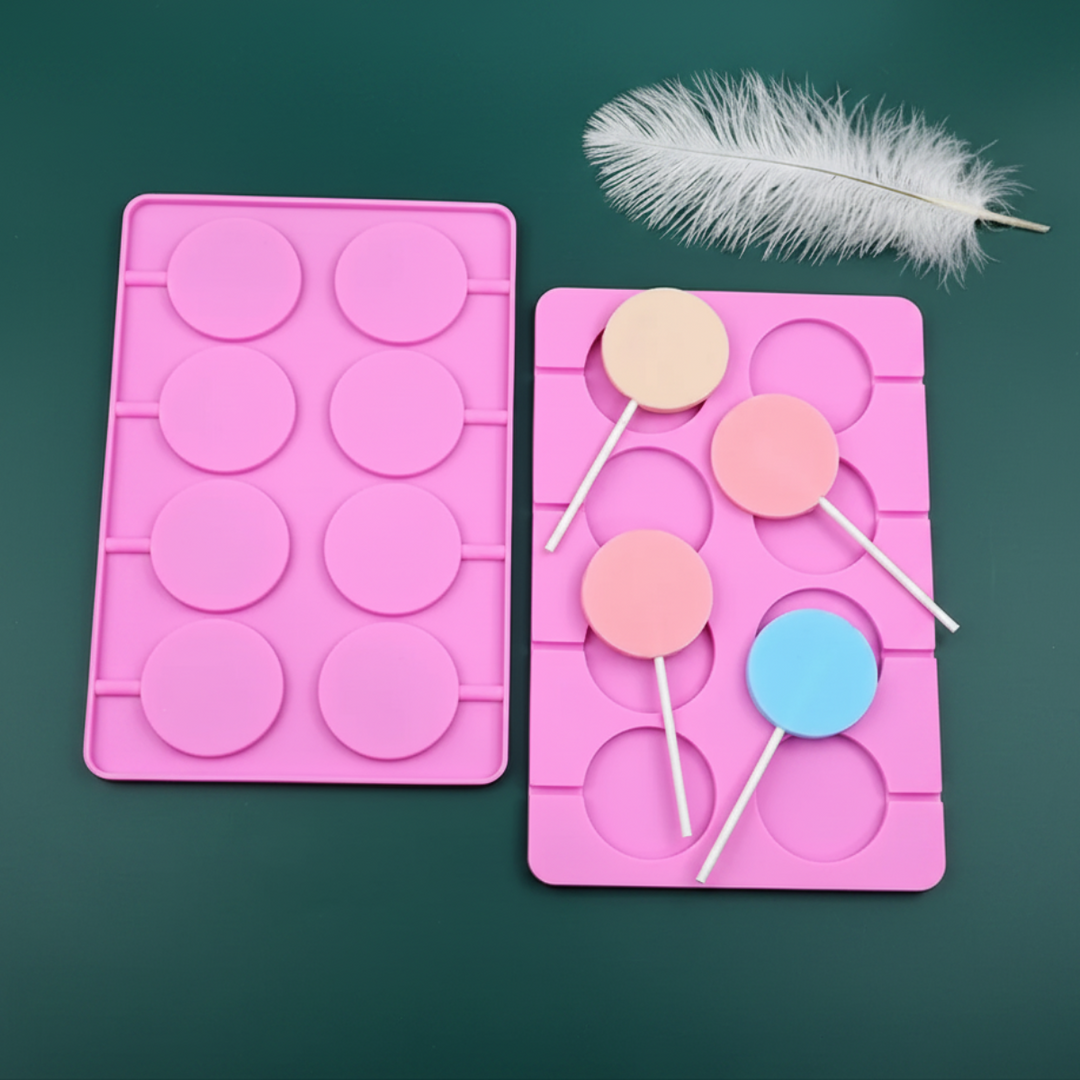 Two pink eight-cavity round molds with pastel lollipops on a dark green background