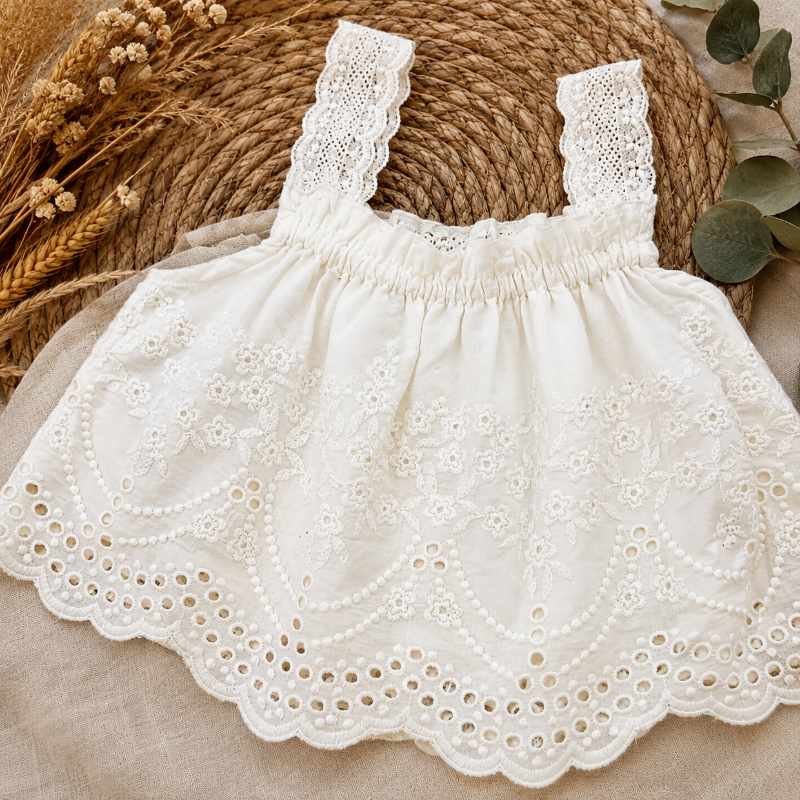 White embroidered top with a scalloped eyelet hem and lace shoulder straps