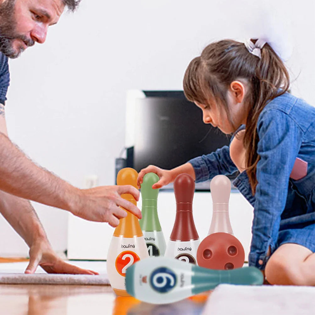 An adult and child setting up colorful bowling pins on an indoor floor.