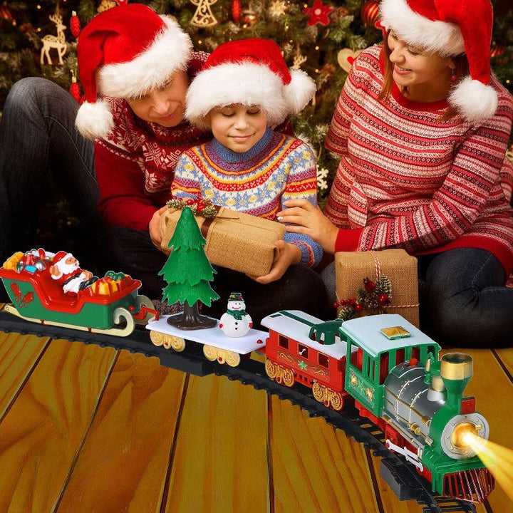 Family in Santa hats gathered beside a red and green Christmas toy train.