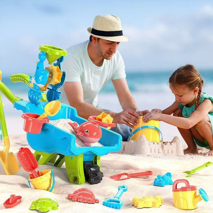 Adult and child building sandcastles beside a blue toy wheelbarrow and colorful sand tools