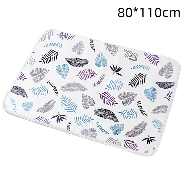 White changing mat with multicolored feather prints, labeled 80 x 110 cm.