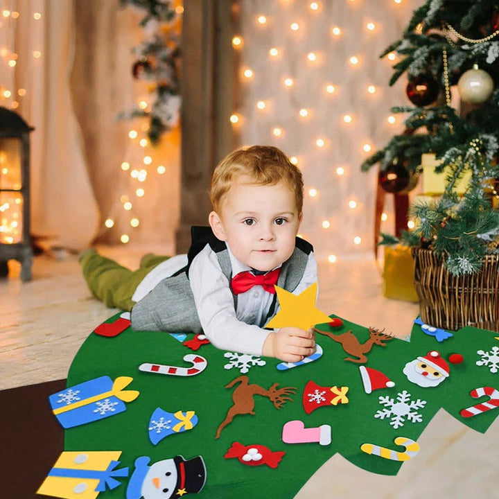 Child lying beside a decorated felt Christmas tree spread on the floor