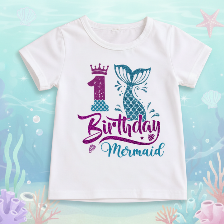 White first-birthday T-shirt with a purple number 1, crown, and teal mermaid tail