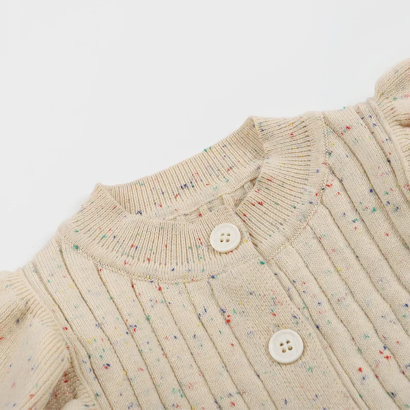 Close-up of the round neckline and front buttons on a flecked beige knit baby romper