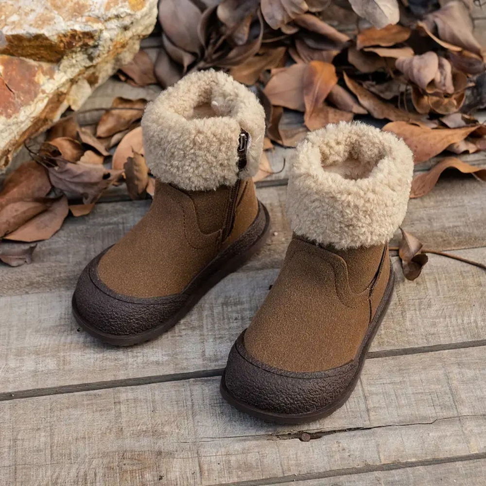 Pair of brown leather winter boots with cream fleece lining on a wooden surface.