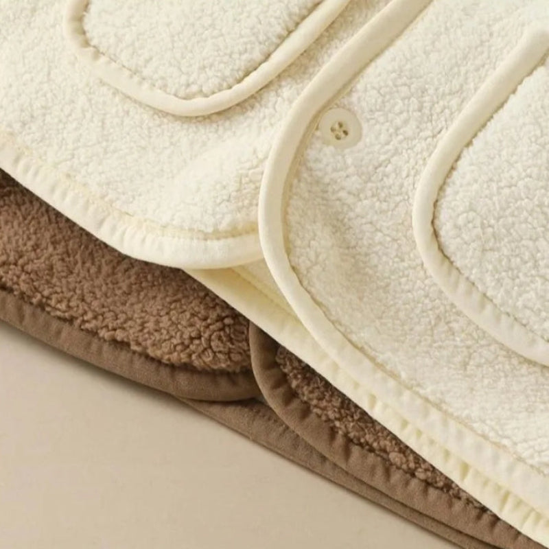 Layered white and brown fleece vests showing rounded hems and edge binding.