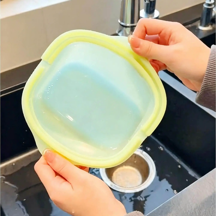 Flexible silicone food storage bag held open above a kitchen sink.