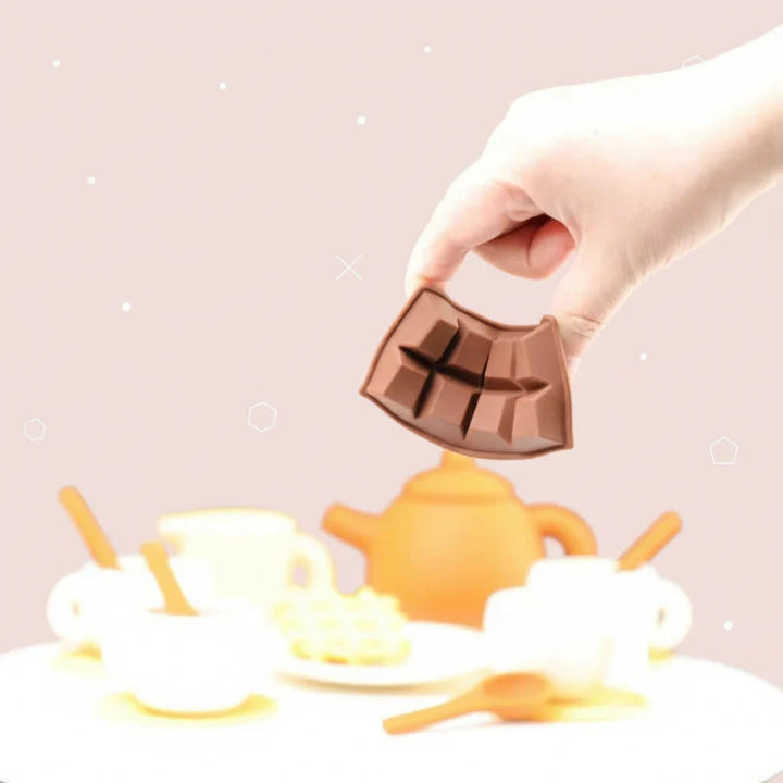 Hand bending the silicone chocolate-bar play piece above a toy tea set