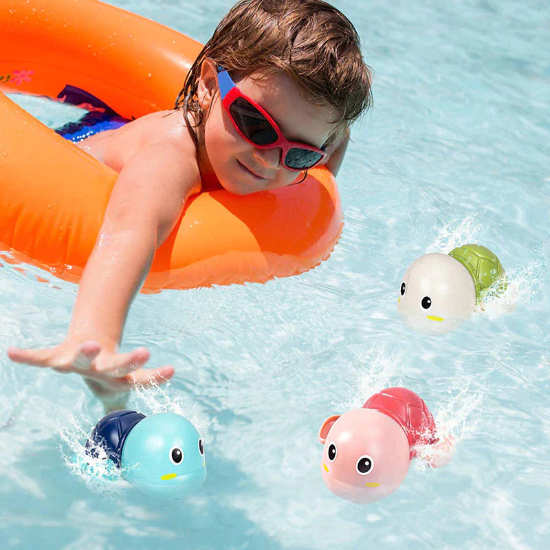 Child on an orange pool float reaching toward three colorful turtle bath toys