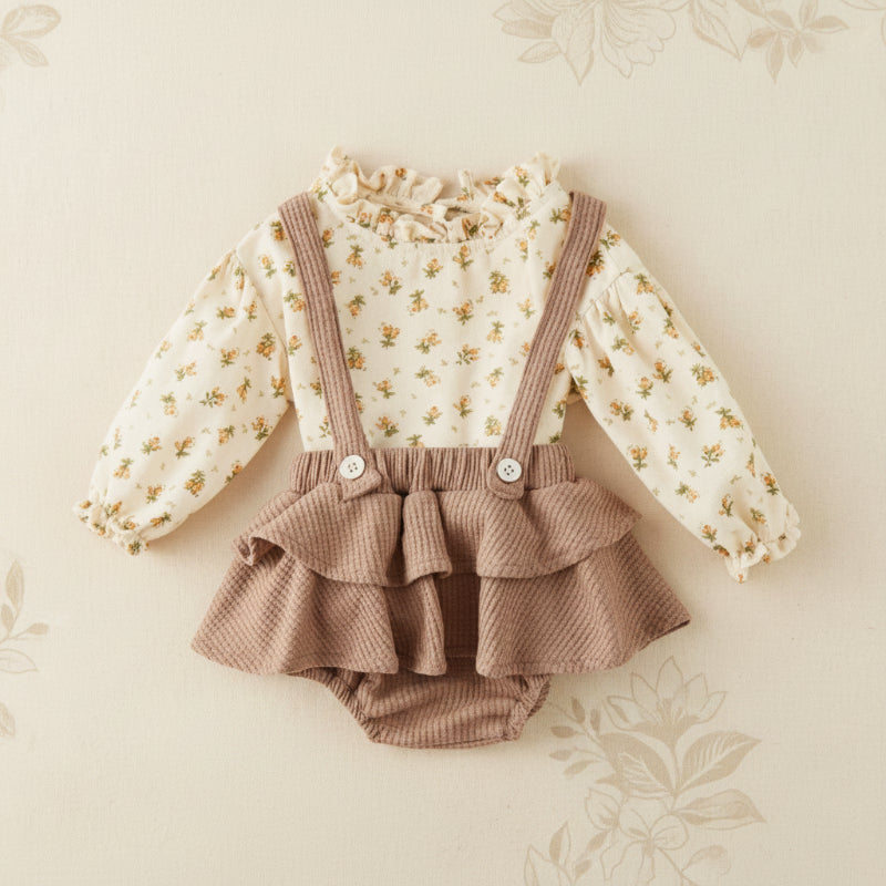 Cream floral long-sleeve blouse with a taupe suspender romper and layered ruffle skirt overlay